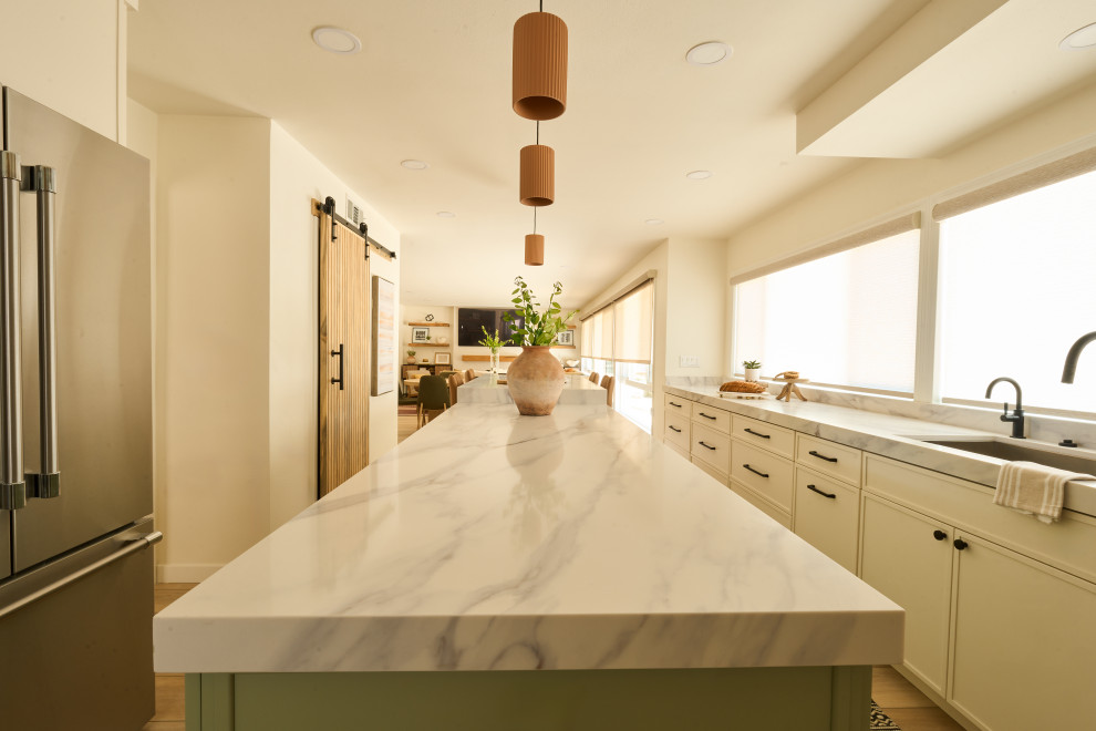 Eat-in kitchen - large transitional u-shaped vinyl floor and brown floor eat-in kitchen idea in Orange County with an undermount sink, shaker cabinets, white cabinets, quartz countertops, white backsplash, quartz backsplash, stainless steel appliances, two islands and white countertops