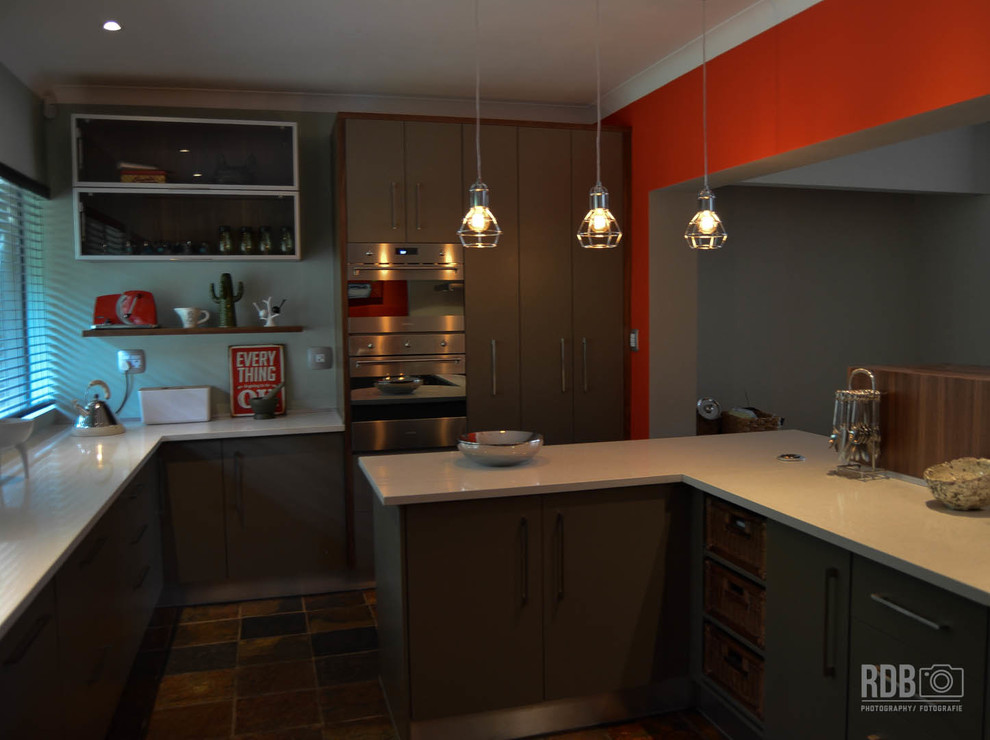 Enclosed kitchen - mid-sized rustic u-shaped slate floor enclosed kitchen idea with a drop-in sink, flat-panel cabinets, green cabinets, quartz countertops, red backsplash, glass sheet backsplash, stainless steel appliances and an island