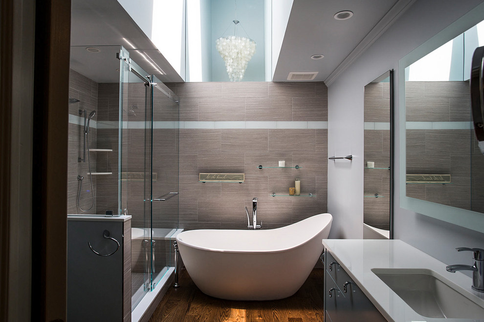 Inspiration for a mid-sized contemporary master bathroom in New York with flat-panel cabinets, grey cabinets, a freestanding tub, a corner shower, brown tile, grey walls, medium hardwood floors, an undermount sink, brown floor and a sliding shower screen.