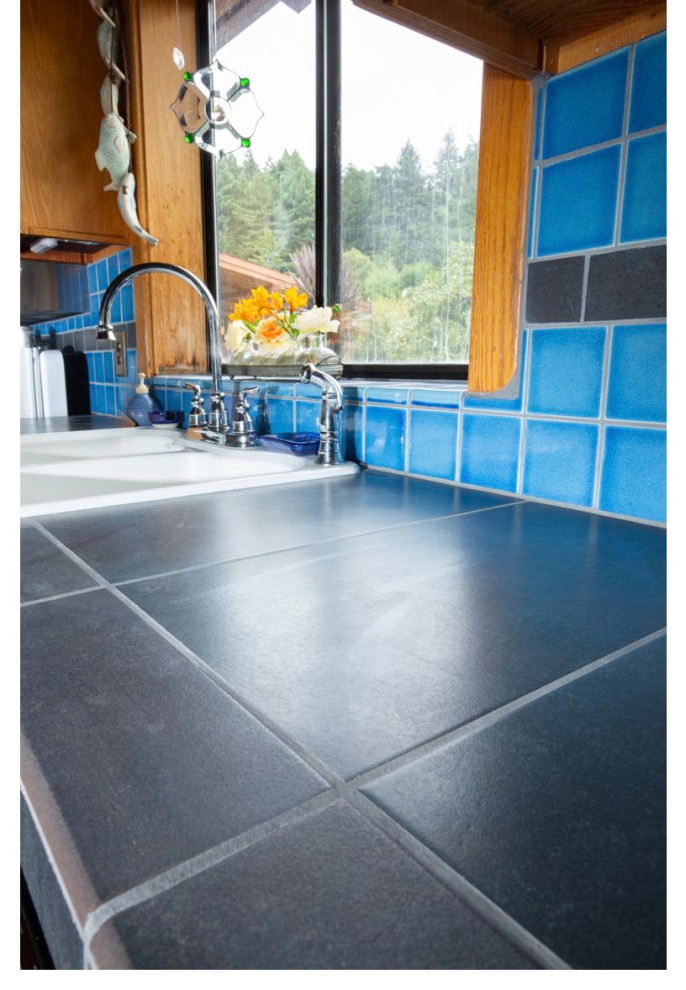 Open concept kitchen - mid-sized rustic galley medium tone wood floor open concept kitchen idea with a double-bowl sink, shaker cabinets, medium tone wood cabinets, tile countertops, blue backsplash, ceramic backsplash, an island and black countertops