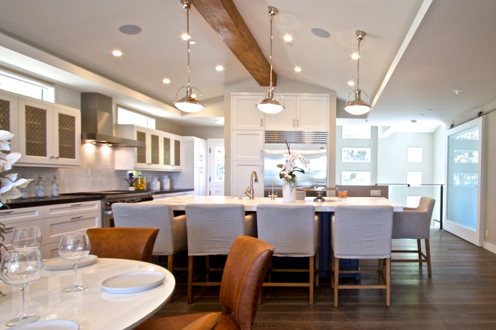Inspiration for a large transitional single-wall dark wood floor eat-in kitchen remodel in Orange County with a farmhouse sink, shaker cabinets, white cabinets, marble countertops, white backsplash, subway tile backsplash, stainless steel appliances and an island