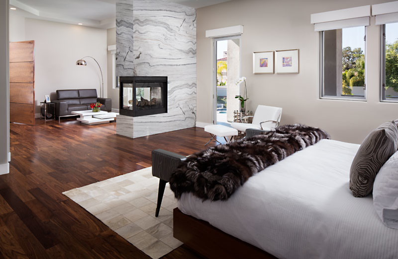 Inspiration for a large contemporary master bedroom in San Diego with grey walls, dark hardwood floors, a two-sided fireplace and a stone fireplace surround.