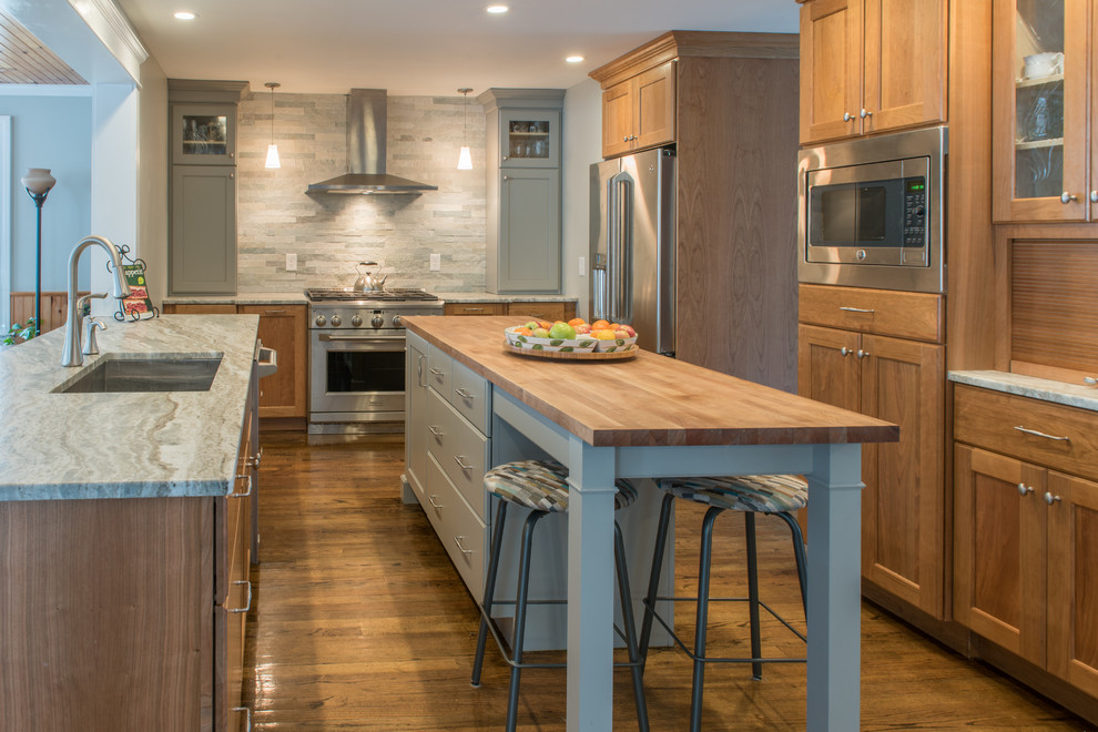 Large transitional u-shaped medium tone wood floor and multicolored floor kitchen pantry photo in Boston with an undermount sink, light wood cabinets, granite countertops, stainless steel appliances, an island, flat-panel cabinets, green backsplash and stone tile backsplash