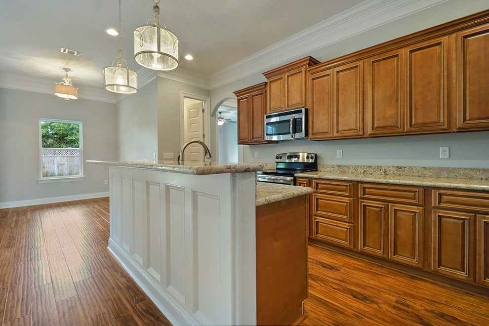 Large transitional l-shaped medium tone wood floor open concept kitchen photo with an undermount sink, raised-panel cabinets, medium tone wood cabinets, granite countertops, stainless steel appliances and an island