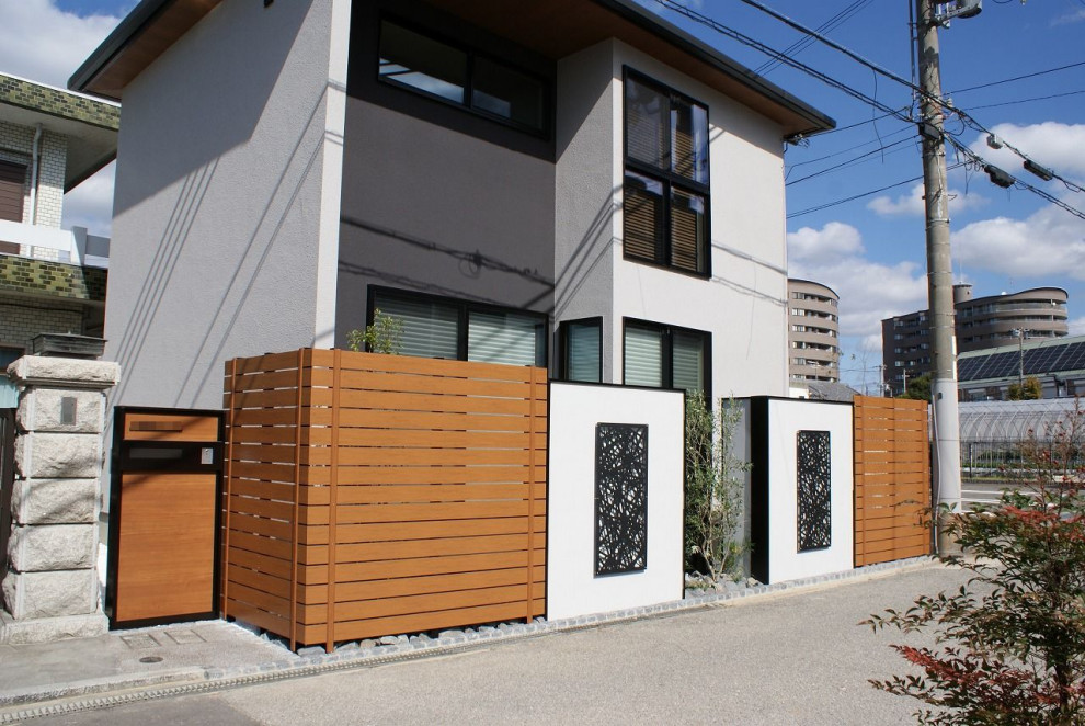 Immagine di un giardino minimalista esposto a mezz'ombra di medie dimensioni e davanti casa in autunno con pavimentazioni in pietra naturale e recinzione in PVC