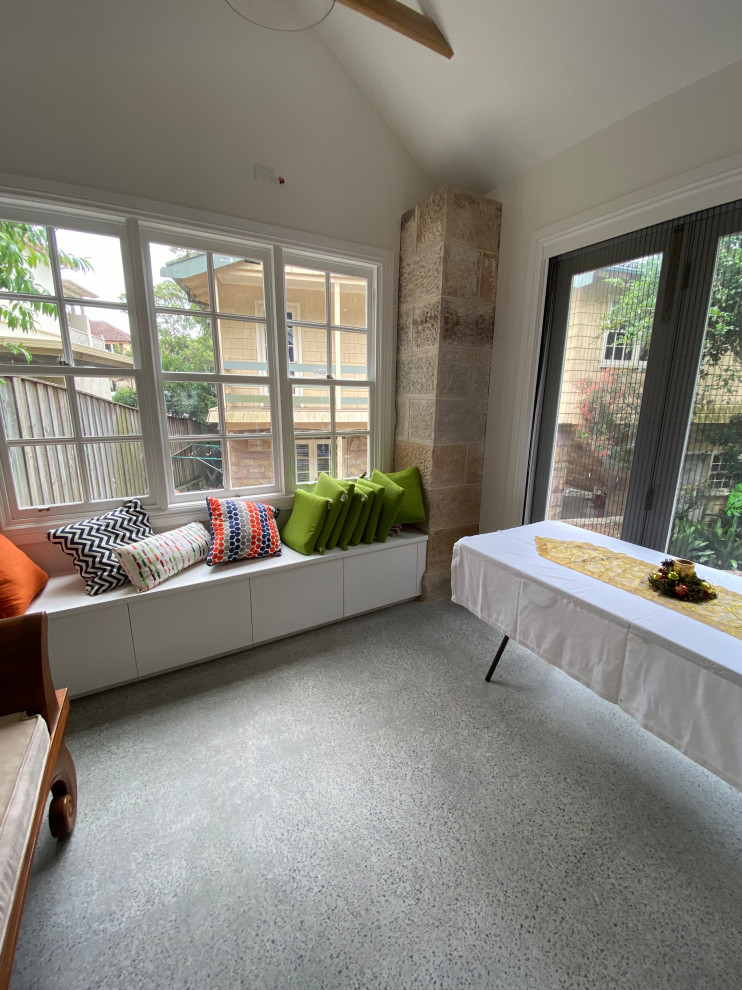 This is an example of a mid-sized traditional enclosed living room in Sydney with white walls, concrete floors, a concealed tv, multi-coloured floor and vaulted.