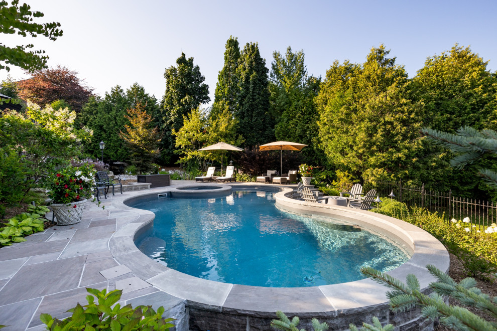 Cette photo montre un piscine avec aménagement paysager arrière chic en forme de haricot avec des pavés en pierre naturelle.