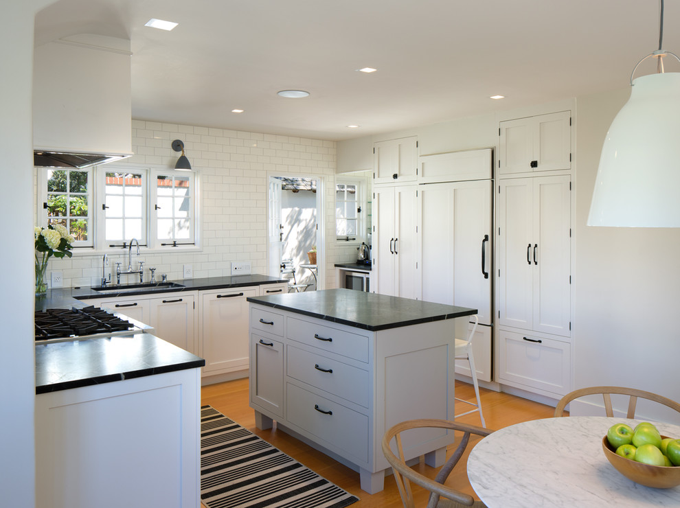 Design ideas for a mid-sized traditional l-shaped eat-in kitchen in San Diego with a single-bowl sink, shaker cabinets, white cabinets, soapstone benchtops, white splashback, subway tile splashback, panelled appliances, medium hardwood floors and with island.