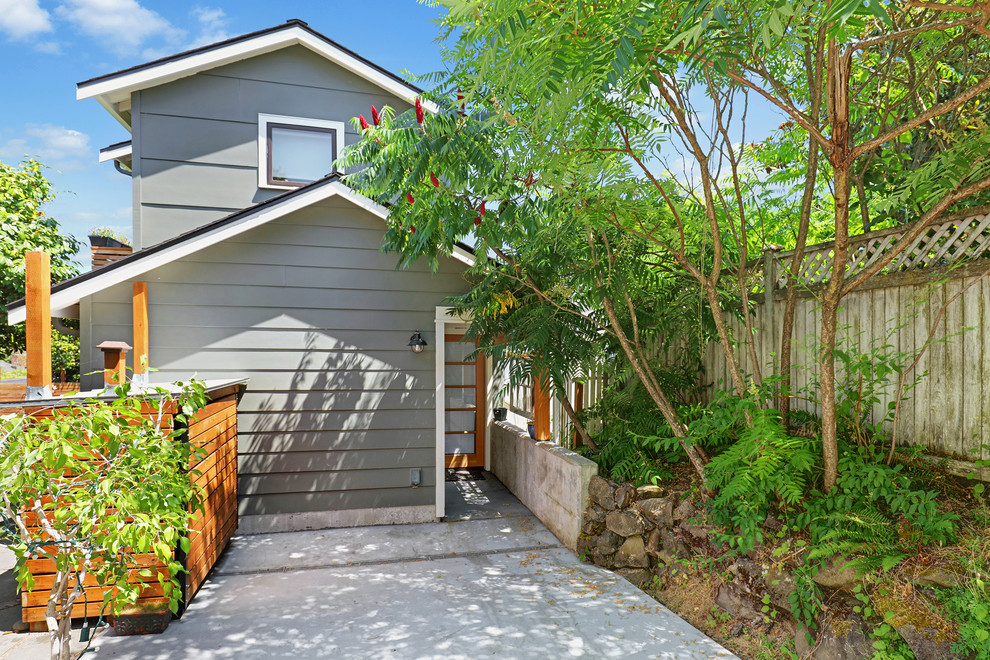 This is an example of a small transitional two-storey grey house exterior in Seattle with concrete fiberboard siding, a gable roof and a green roof.