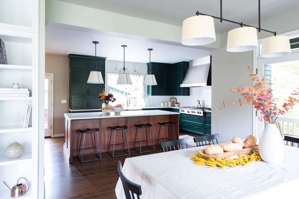This is an example of a mid-sized transitional l-shaped eat-in kitchen in Seattle with a farmhouse sink, shaker cabinets, green cabinets, white splashback, subway tile splashback, panelled appliances, dark hardwood floors, with island, brown floor, green benchtop and quartz benchtops.