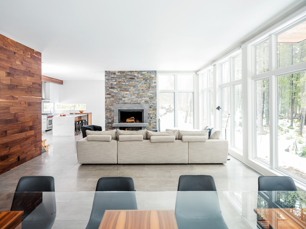Mid-sized modern open concept living room in Burlington with white walls, ceramic floors, a wood stove, a stone fireplace surround, no tv and beige floor.