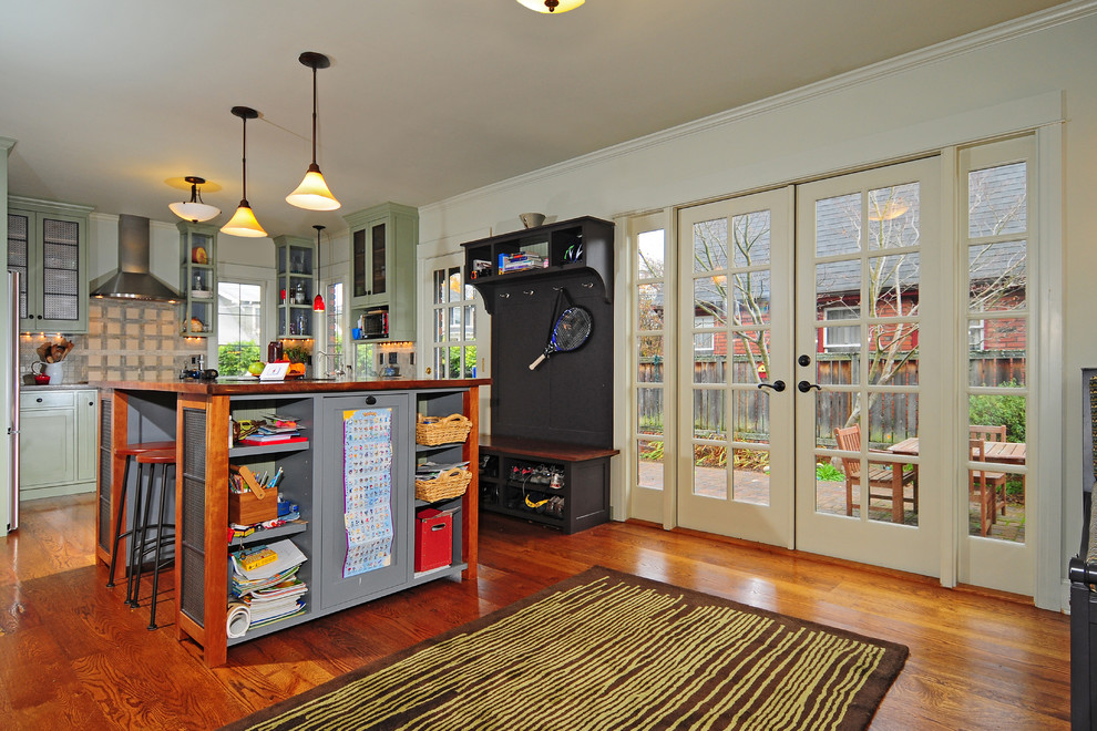 Example of a mid-sized transitional u-shaped dark wood floor kitchen pantry design in Seattle with a farmhouse sink, shaker cabinets, green cabinets, wood countertops, green backsplash, stone tile backsplash, stainless steel appliances, gray walls and an island