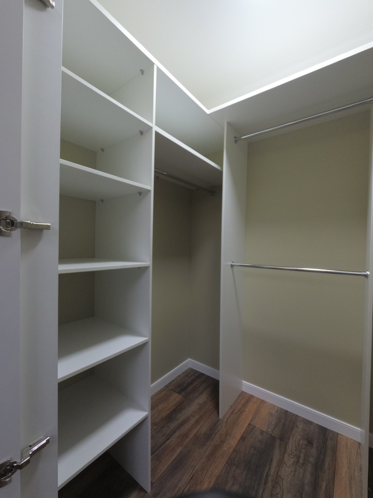 Mid-sized transitional gender-neutral walk-in wardrobe in Moscow with louvered cabinets, white cabinets, laminate floors and brown floor.
