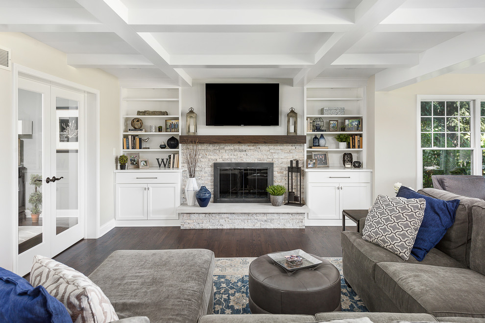 Design ideas for a large transitional open concept family room in Chicago with beige walls, dark hardwood floors, a standard fireplace, a wall-mounted tv, a stone fireplace surround and brown floor.