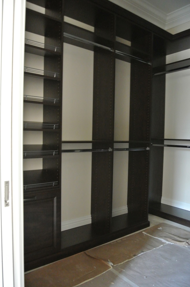Large traditional gender neutral walk-in wardrobe in Miami with raised-panel cabinets, dark wood cabinets and travertine flooring.