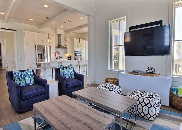 Photo of a large beach style open concept living room in Austin with white walls, medium hardwood floors, a wall-mounted tv and brown floor.