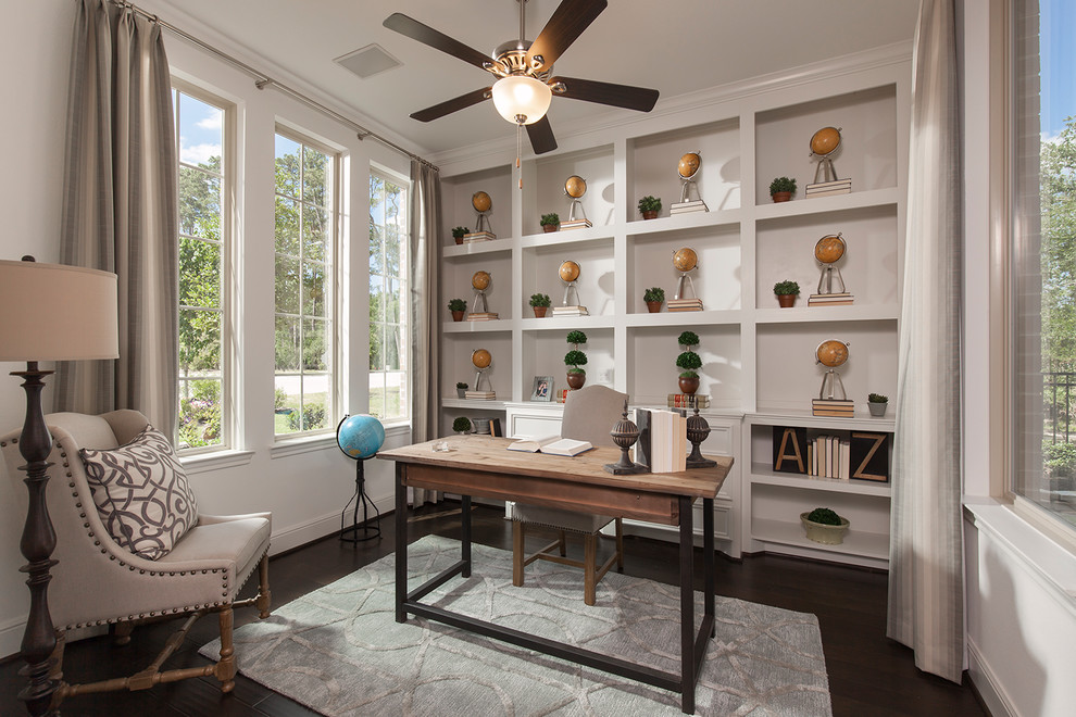 Photo of a traditional home office in Houston with white walls, dark hardwood floors, a freestanding desk and brown floor.