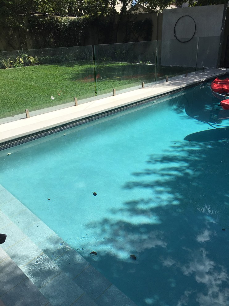This is an example of a contemporary backyard pool in Perth with natural stone pavers.