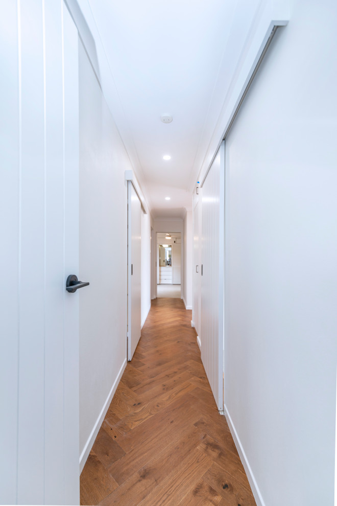 Design ideas for a small midcentury hallway in Central Coast with white walls and light hardwood floors.
