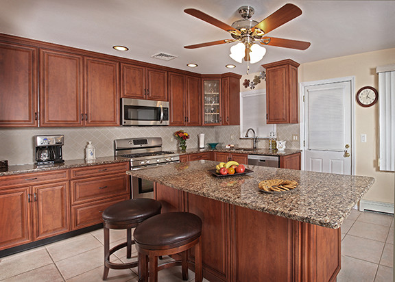 Eat-in kitchen - rustic l-shaped eat-in kitchen idea with an integrated sink, raised-panel cabinets, dark wood cabinets, quartz countertops, beige backsplash, subway tile backsplash and stainless steel appliances