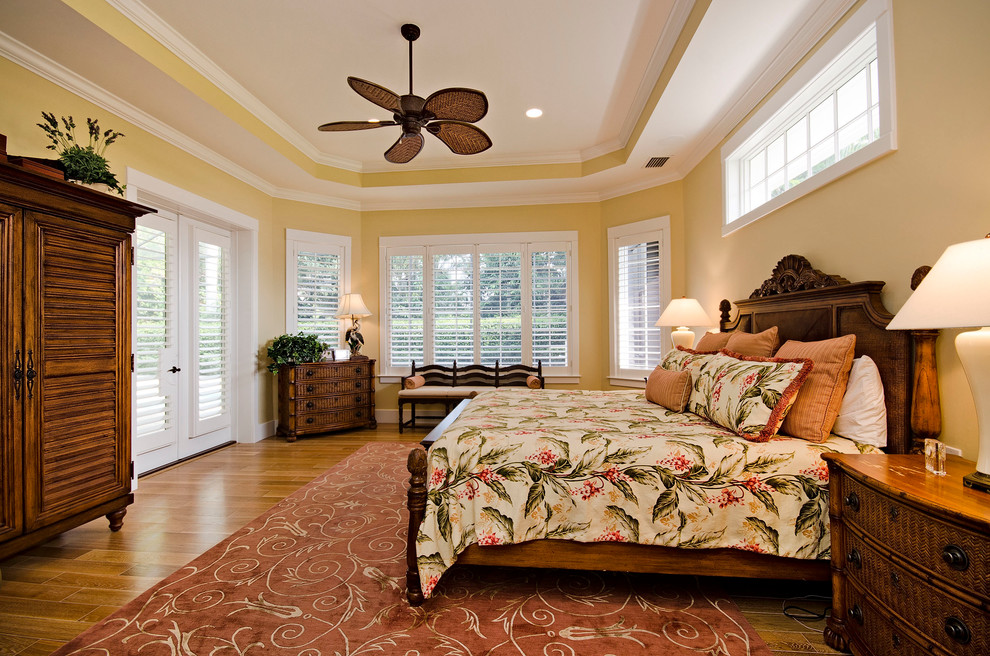 Inspiration for a large tropical master bedroom in New York with yellow walls.