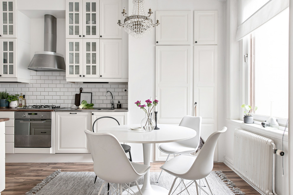 This is an example of a large transitional kitchen/dining combo in Gothenburg with white walls, brown floor and medium hardwood floors.