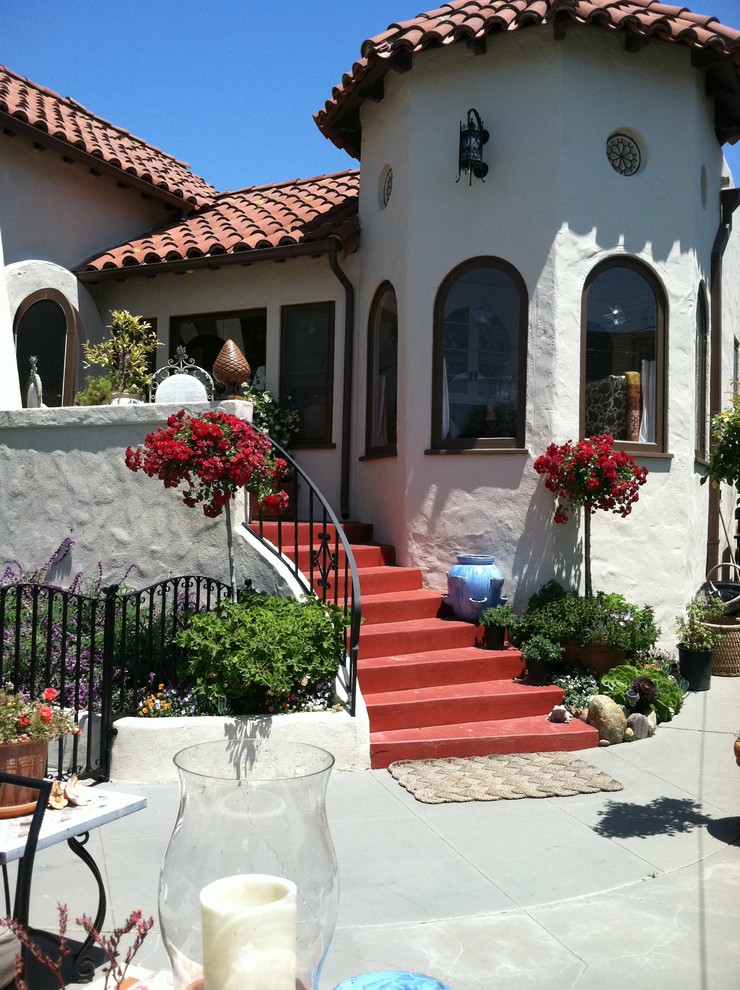 This is an example of a large stamped concrete metal railing porch design in San Diego with a roof extension.