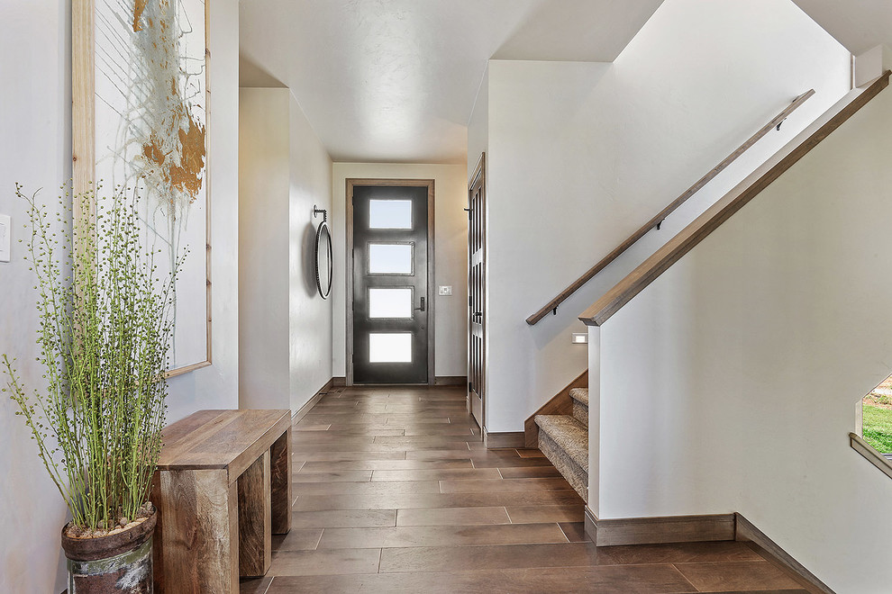 Example of a trendy medium tone wood floor and brown floor front door design with gray walls and a black front door