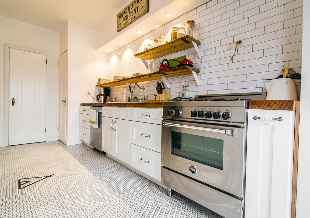 Inspiration for a small midcentury single-wall separate kitchen in New York with a double-bowl sink, shaker cabinets, white cabinets, wood benchtops, white splashback, subway tile splashback, stainless steel appliances, porcelain floors and no island.