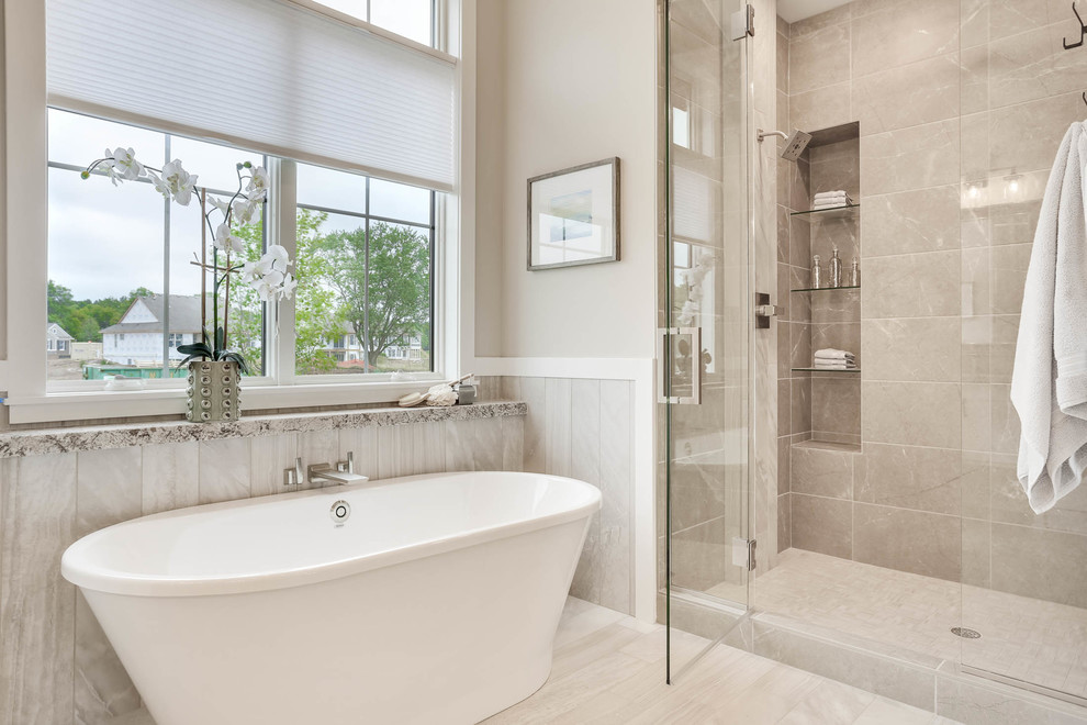 This is an example of a transitional bathroom in Minneapolis with a freestanding tub, gray tile, grey walls and grey floor.