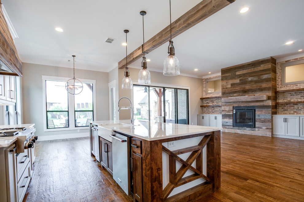 Design ideas for a large country l-shaped open plan kitchen in Dallas with a farmhouse sink, shaker cabinets, white cabinets, granite benchtops, white splashback, ceramic splashback, stainless steel appliances, medium hardwood floors, with island and brown floor.