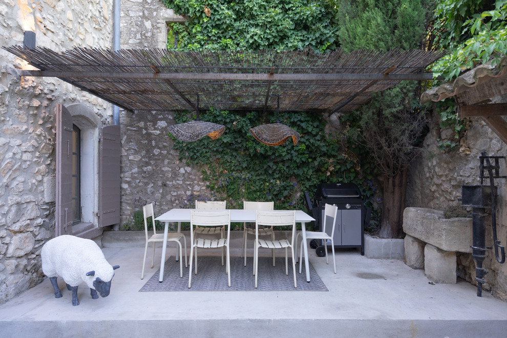 This is an example of a mid-sized mediterranean courtyard patio in Other with an outdoor kitchen, concrete slab and a pergola.