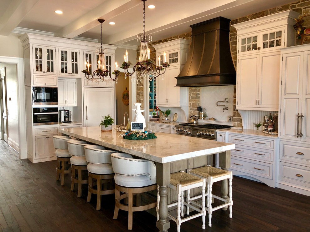 Traditional l-shaped kitchen in DC Metro with white cabinets, white splashback, ceramic splashback, dark hardwood floors, with island, brown floor, raised-panel cabinets, panelled appliances and white benchtop.