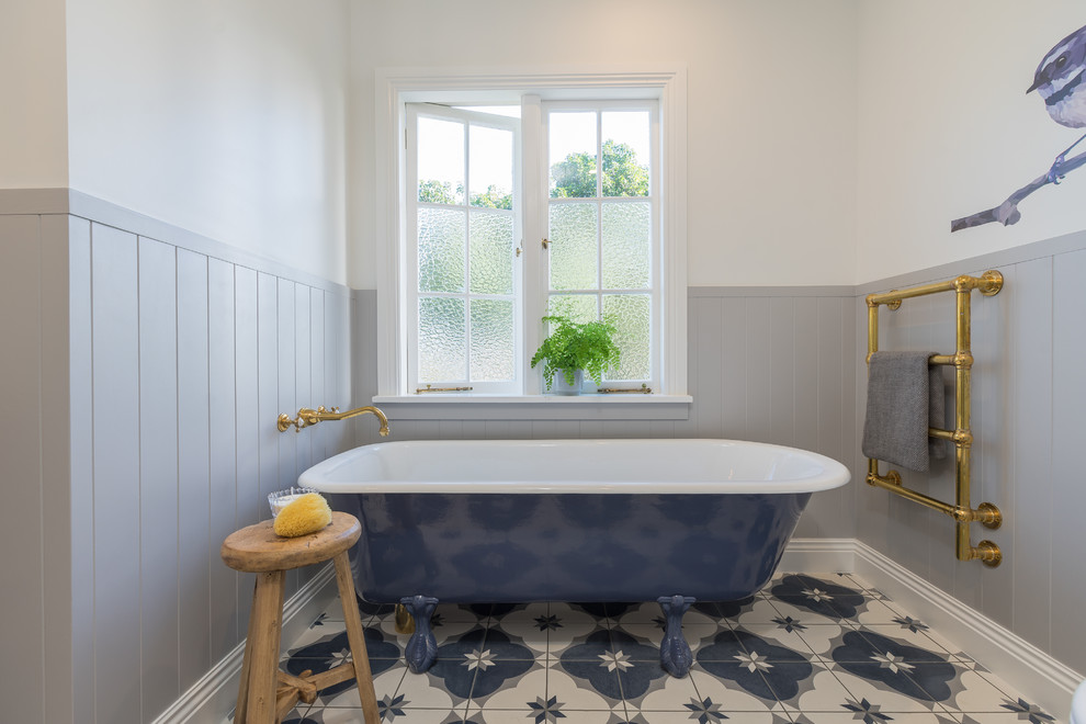 This is an example of a mid-sized transitional kids bathroom in Auckland with a claw-foot tub, white walls, cement tiles and multi-coloured floor.