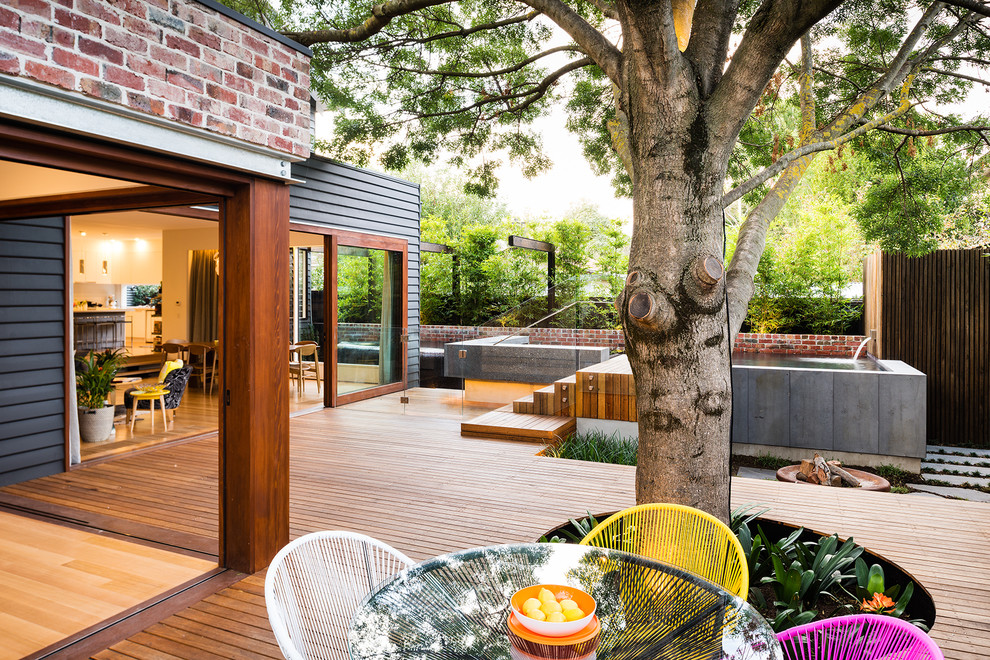 Contemporary backyard deck in Melbourne with a water feature and no cover.