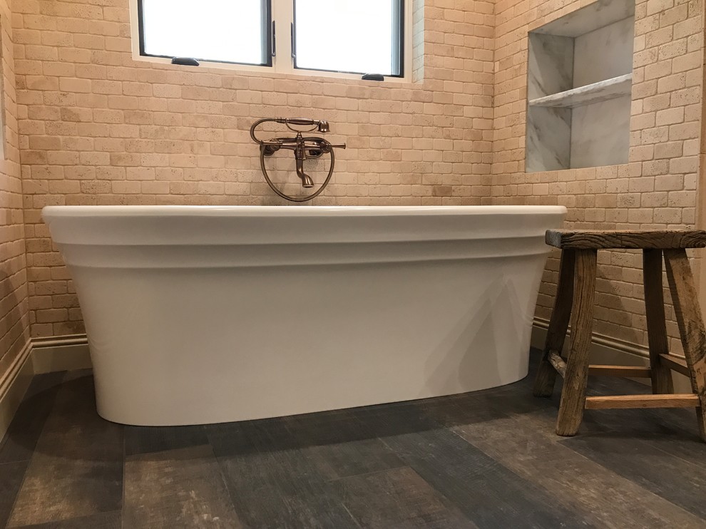 Photo of a mid-sized mediterranean master bathroom in Phoenix with raised-panel cabinets, dark wood cabinets, a freestanding tub, an alcove shower, a one-piece toilet, beige tile, stone tile, beige walls, dark hardwood floors, a vessel sink, marble benchtops, brown floor and a hinged shower door.