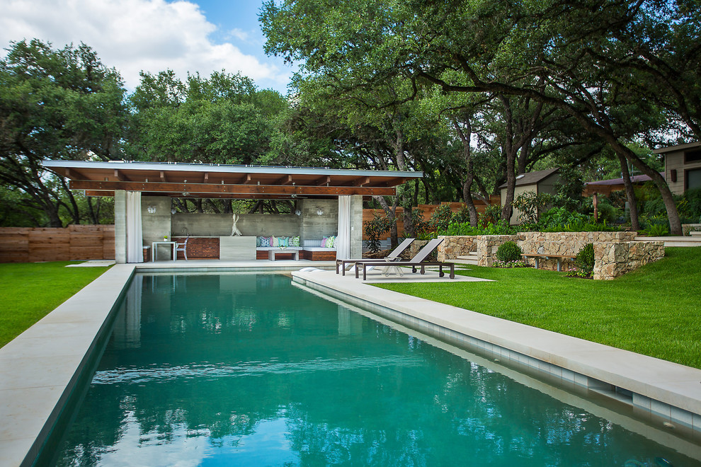 Photo of a large contemporary backyard rectangular lap pool in Austin with a pool house and natural stone pavers.