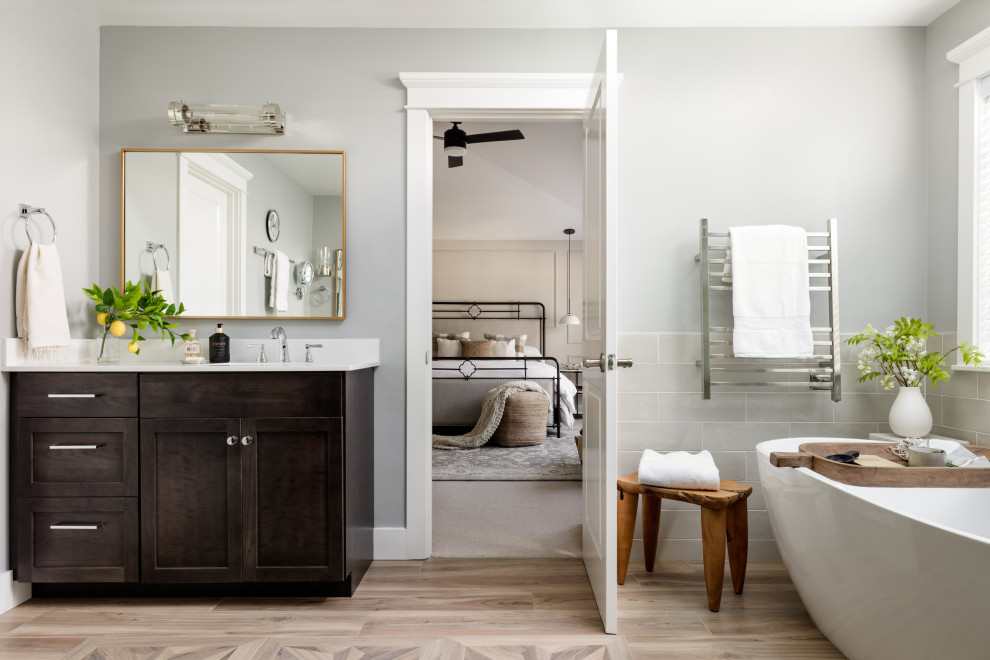 Inspiration for a large transitional master bathroom in Seattle with shaker cabinets, black cabinets, a freestanding tub, a one-piece toilet, white tile, ceramic tile, white walls, ceramic floors, engineered quartz benchtops, brown floor, white benchtops, a shower seat, a double vanity and a built-in vanity.