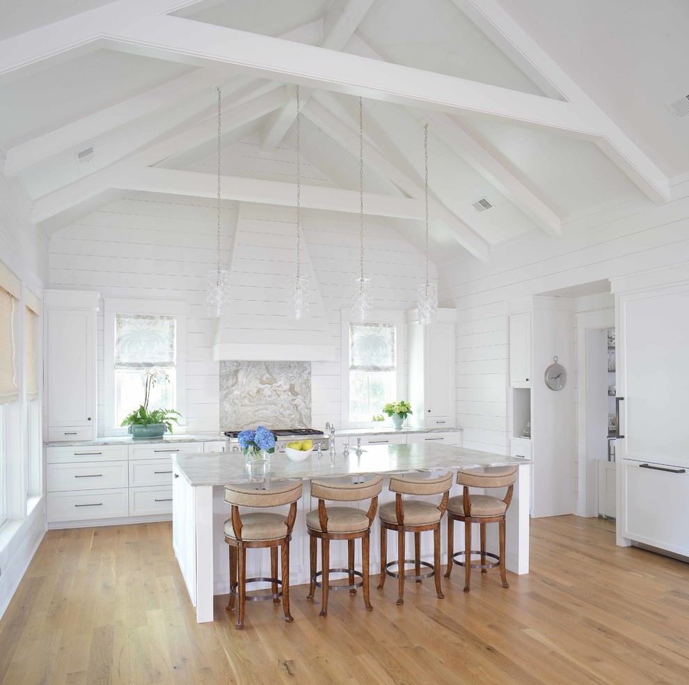 This is an example of a beach style u-shaped kitchen in Charleston with shaker cabinets, white cabinets, panelled appliances, medium hardwood floors, with island and brown floor.