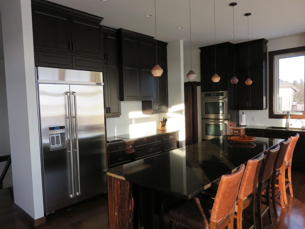 Inspiration for a large transitional l-shaped dark wood floor and brown floor open concept kitchen remodel with recessed-panel cabinets, dark wood cabinets, quartz countertops, stainless steel appliances, an island and an undermount sink