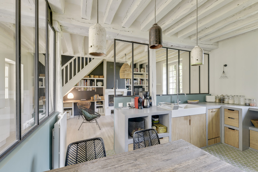 This is an example of a large industrial l-shaped separate kitchen in Paris with a farmhouse sink, open cabinets, light wood cabinets, concrete benchtops, green splashback, black appliances, cement tiles, no island, green floor and grey benchtop.