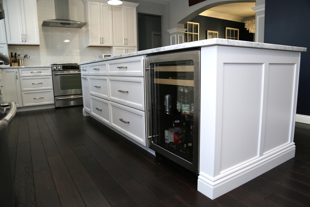Eat-in kitchen - large transitional l-shaped dark wood floor eat-in kitchen idea in Chicago with recessed-panel cabinets, stainless steel appliances, an island, a farmhouse sink, white cabinets, quartz countertops, white backsplash and subway tile backsplash