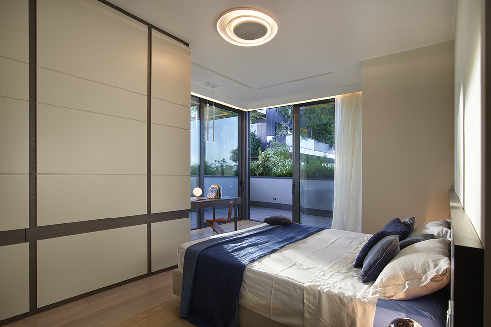 Photo of a mid-sized contemporary master bedroom in Milan with beige walls and medium hardwood floors.