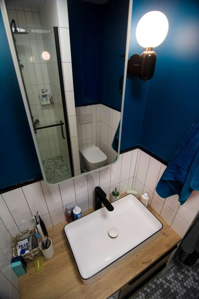 Идея дизайна: маленькая ванная комната со стиральной машиной в скандинавском стиле с плоскими фасадами, светлыми деревянными фасадами, душем в нише, инсталляцией, белой плиткой, плиткой кабанчик, синими стенами, полом из мозаичной плитки, душевой кабиной, настольной раковиной, столешницей из дерева, серым полом, душем с распашными дверями, бежевой столешницей, тумбой под одну раковину и напольной тумбой для на участке и в саду