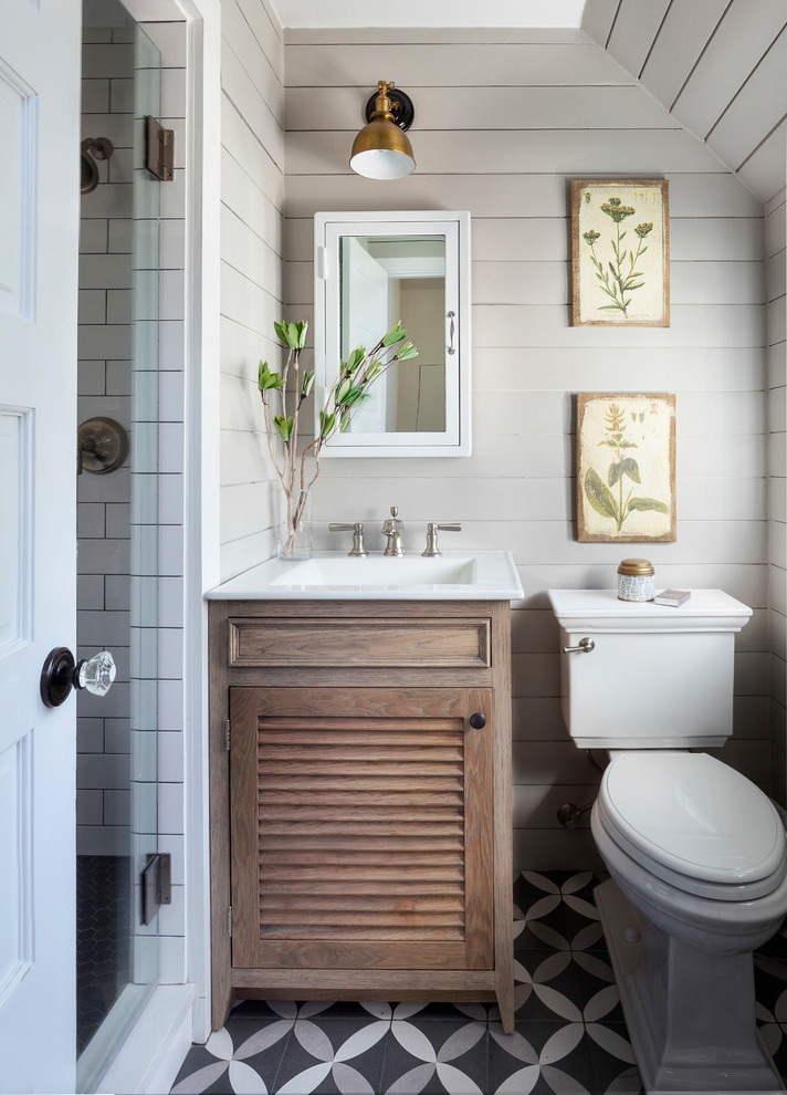 Photo of a small country 3/4 bathroom in Denver with a two-piece toilet, white tile, subway tile, multi-coloured floor, a hinged shower door, white benchtops, light wood cabinets, beige walls, an integrated sink and louvered cabinets.