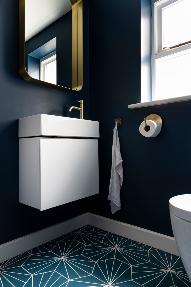 Design ideas for a small contemporary cloakroom in London with flat-panel cabinets, white cabinets, a wall mounted toilet, blue walls, ceramic flooring, a wall-mounted sink, blue floors, a feature wall and a floating vanity unit.