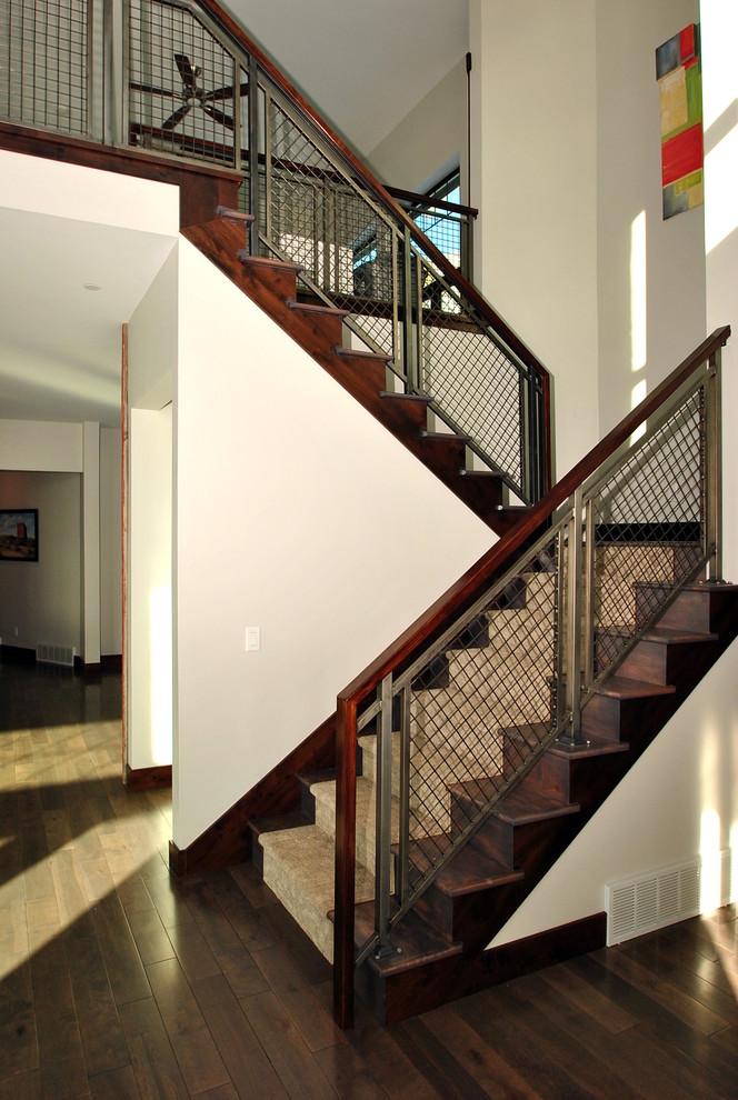 Photo of a large arts and crafts carpeted u-shaped staircase in Salt Lake City with wood risers and metal railing.
