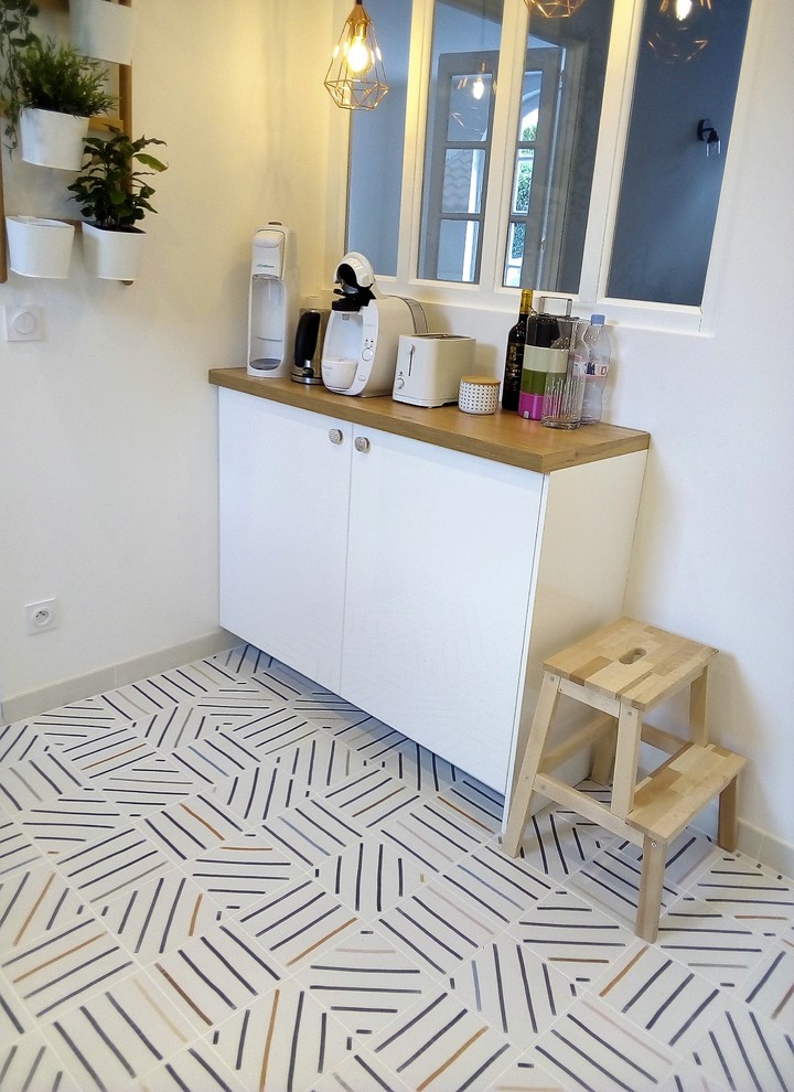 This is an example of a small scandinavian l-shaped open plan kitchen in Montpellier with an undermount sink, beaded inset cabinets, white cabinets, wood benchtops, brown splashback, timber splashback, panelled appliances, cement tiles, no island, multi-coloured floor and brown benchtop.