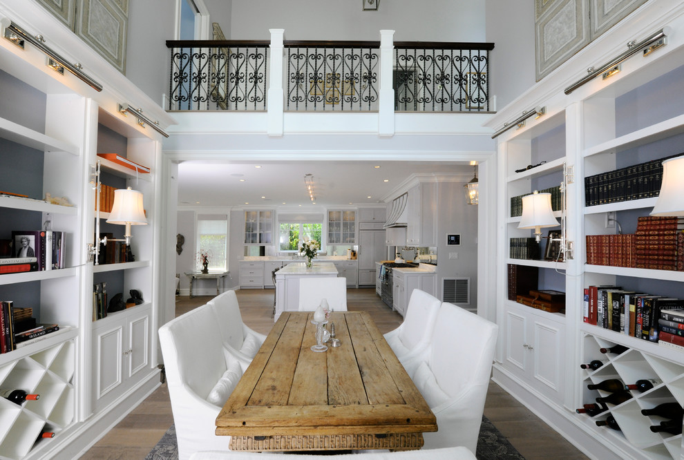 This is an example of a traditional open plan dining in New York with white walls and light hardwood floors.