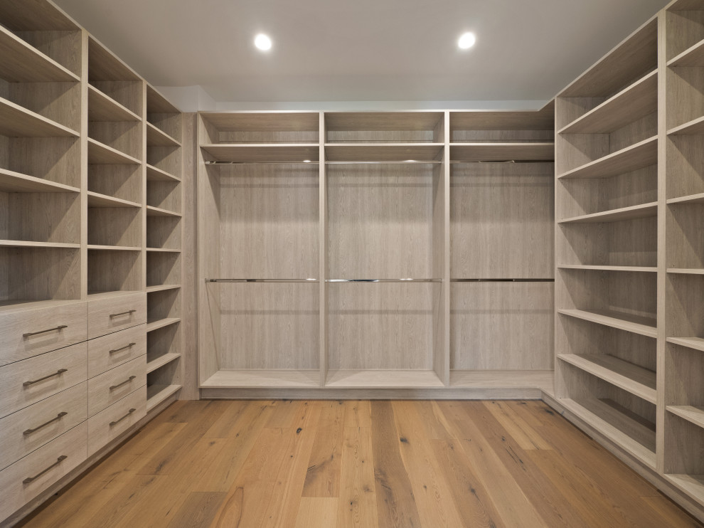This is an example of a large country gender-neutral walk-in wardrobe in Los Angeles with flat-panel cabinets and light hardwood floors.